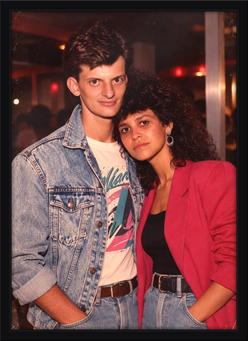 Quadro decorativo de casal em visual dos anos 80, com jaqueta jeans e blazer vermelho